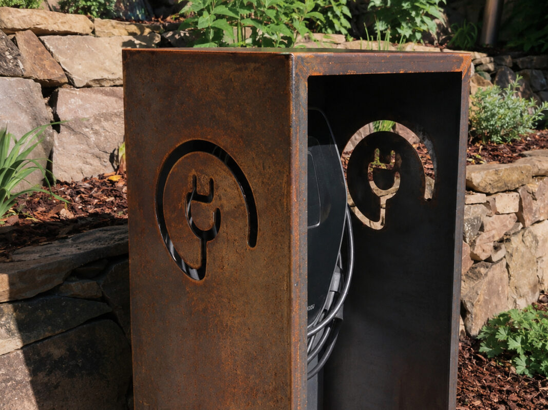 Nahaufnahme der Cortenstahl-Wallbox mit Stecker-Ausschnitt und sichtbar beginnender Rostpatina im Außenbereich aufgenommen