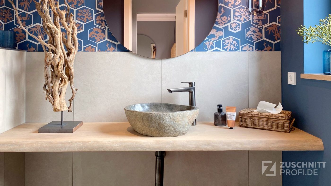 Modern badkamer met houten wastafel, stenen wasbak, ronde spiegelwand en blauw behang.