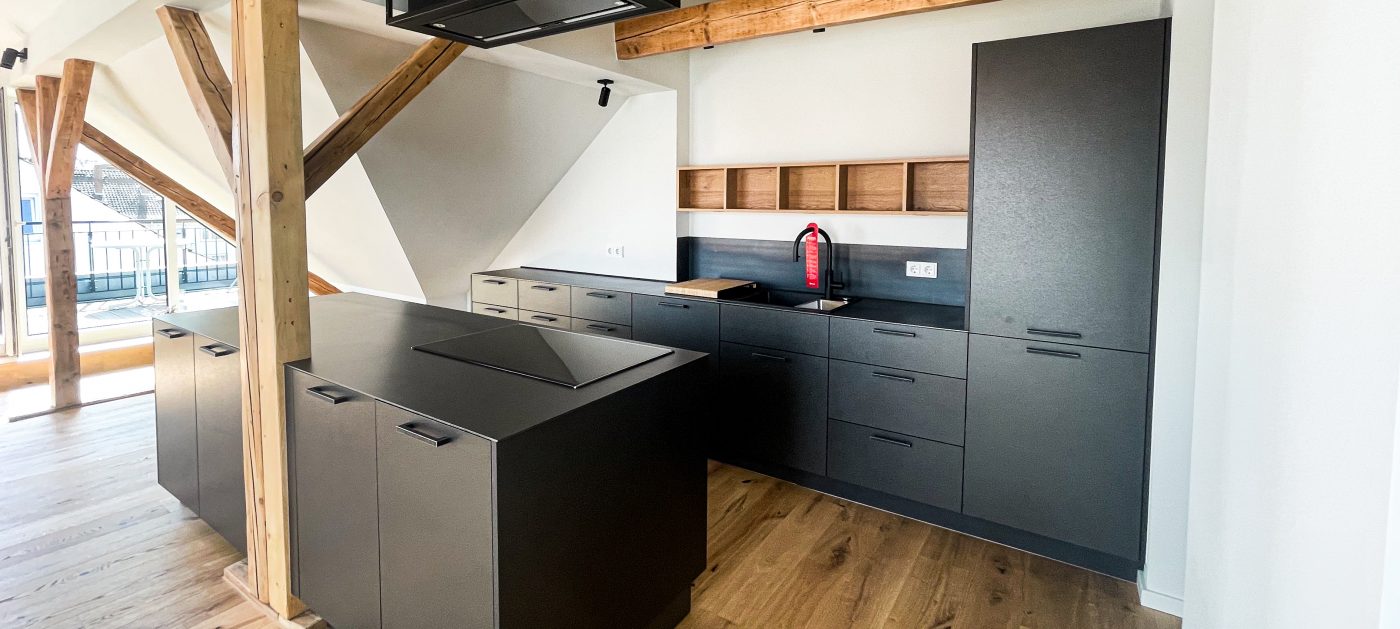Moderne Küche mit maßgefertigten Arbeitsplatten und Fronten aus Schwarzstahl, die einen industriellen Look verleihen.