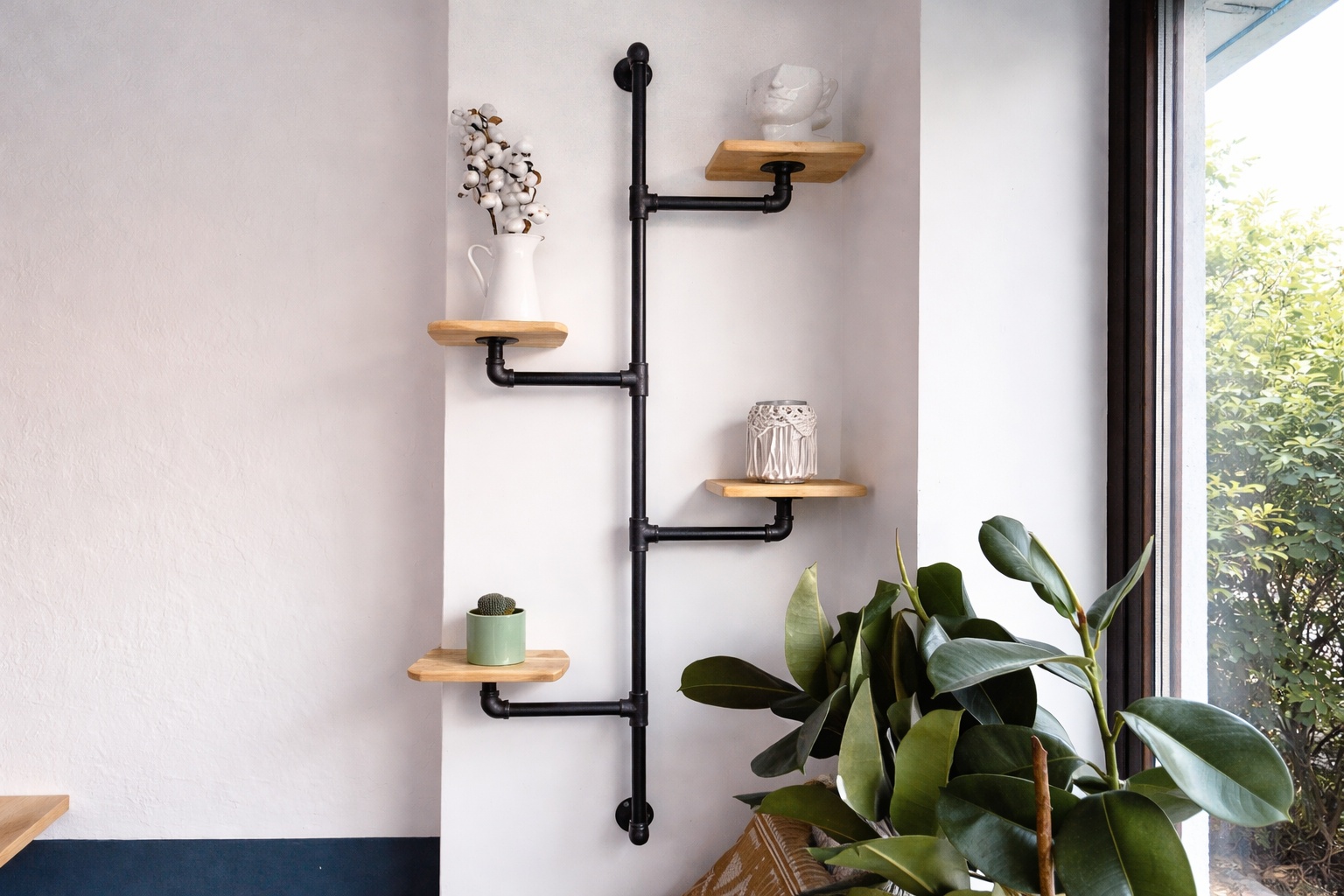 Ein Wandregal aus Rundrohr Stahl trägt Holzablagen mit Pflanzen an der Wand.