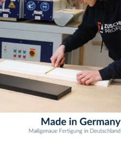Ein Mitarbeiter misst eine weiße Dekorplatte bei der Fertigung nach Maß.