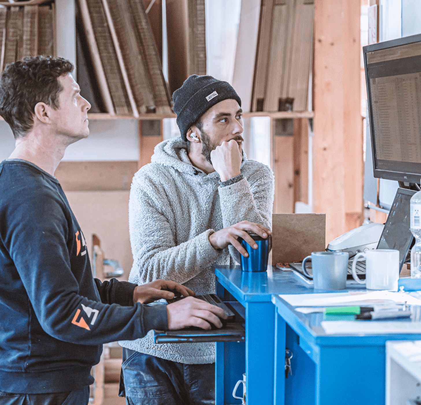 Zwei Mitarbeiter von Zuschnittprofi.de besprechen konzentriert Arbeitsabläufe an einem Computer.
