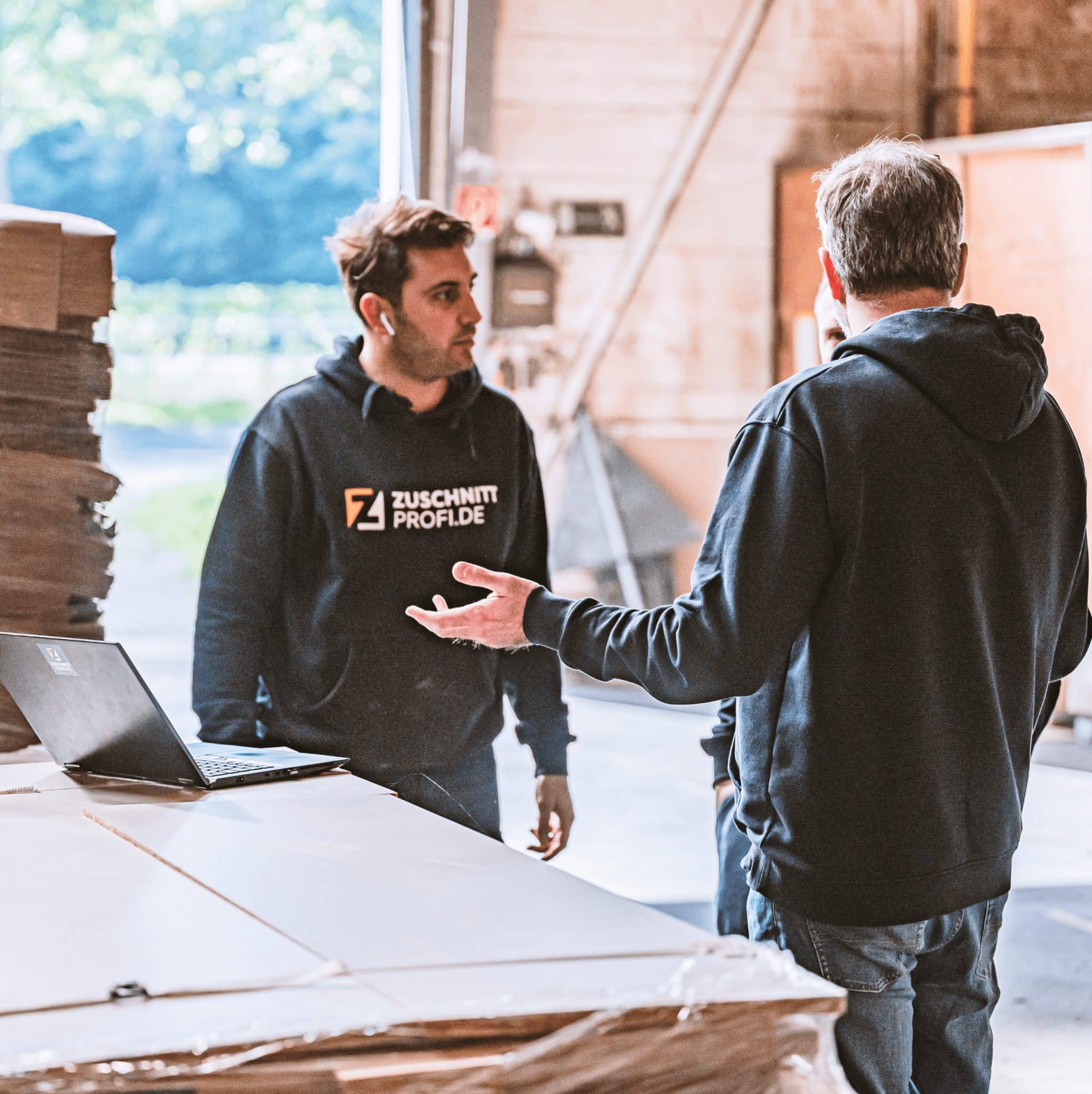 Zwei Mitarbeiter von Zuschnittprofi.de besprechen gemeinsam die nächsten Schritte in der Produktion.