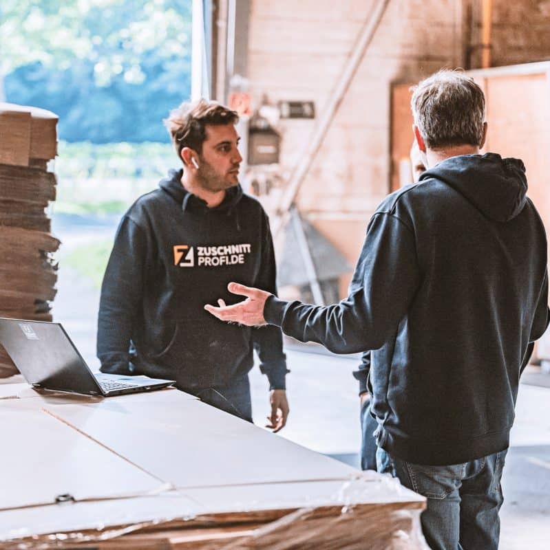 Zwei Mitarbeiter von Zuschnittprofi.de besprechen gemeinsam die nächsten Schritte in der Produktion.
