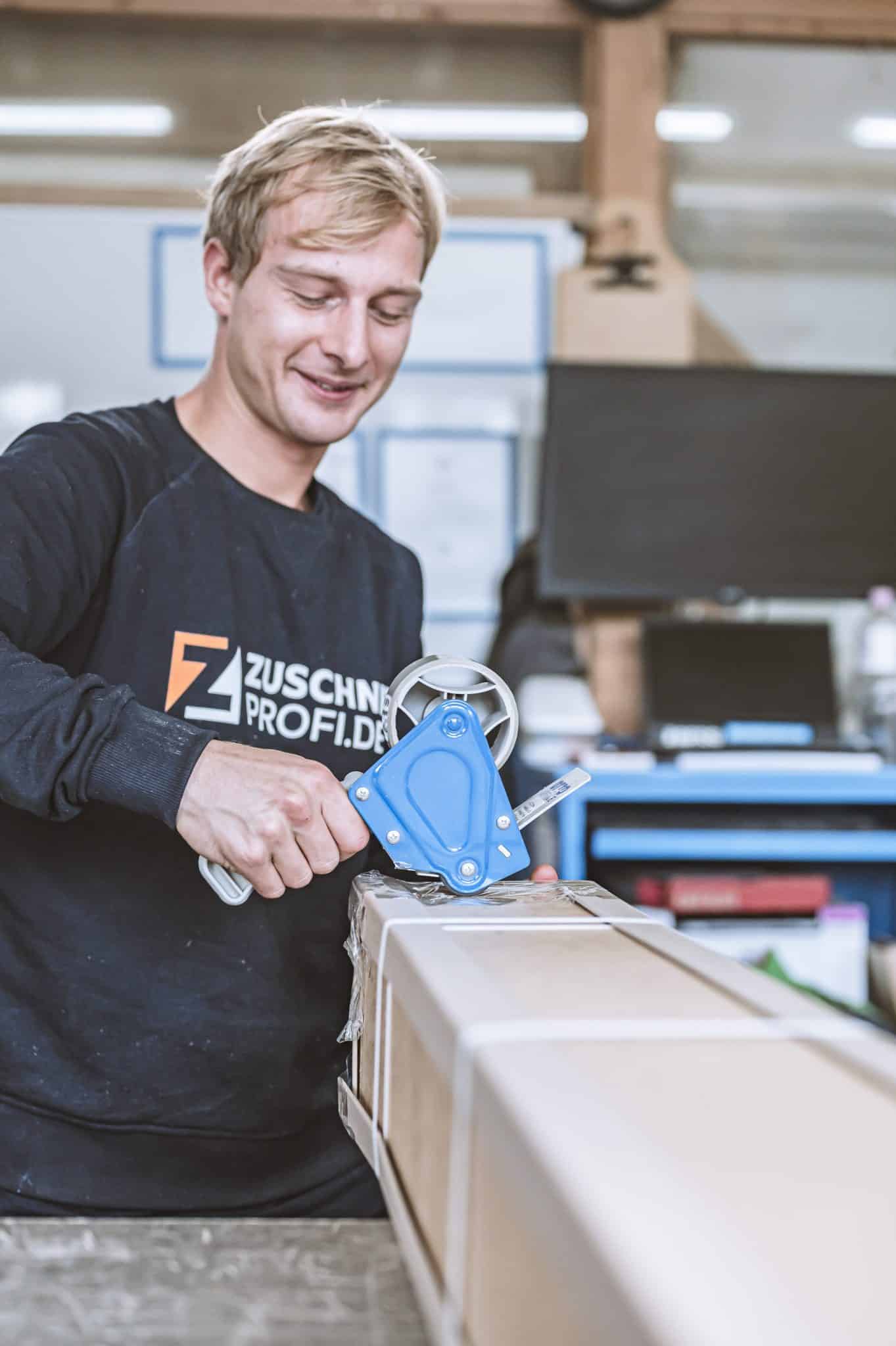 Ein Mitarbeiter von Zuschnittprofi.de verpackt sorgfältig Materialien.